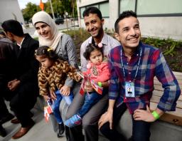 Un homme assis avec une famille de deux enfants; tous les adultes sourient.