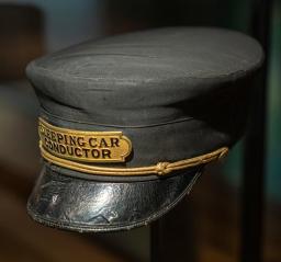 Casquette en tissu noir orné d’un badge sur le devant qui dit : « sleeping car conductor » en anglais.