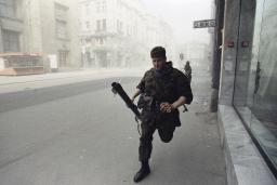 Un soldat court dans une rue vide et enfumée