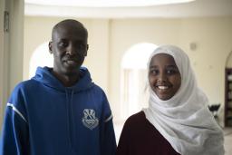 Un homme se tient à côté d’une jeune femme portant un hidjab.