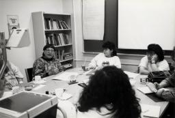 Un groupe de femmes assises autour d’une table couverte de papiers. 