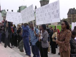 Une foule de protestataires tenant des panneaux sur les marches du Parlement.
