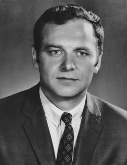 Portrait en noir et blanc d’un homme portant un complet et une cravate.