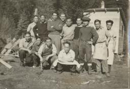 Un groupe d’hommes pose pour une photo avec des arbres en arrière-plan.