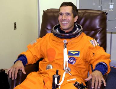 Un homme souriant dans un uniforme d'astronaute orange.