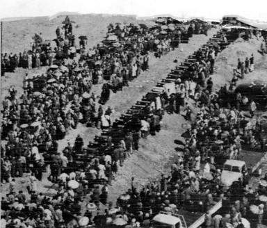 Photo aérienne d’une longue file de cercueils entourés d’une grande foule. 
