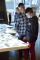 Un homme adulte et un adolescent se tiennent l'un à côté de l'autre et regardent une table interactive.