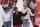 Deux femmes et un homme se tiennent debout sur une scène, tandis qu’un groupe de personnes vêtues d’une chemise blanche se tient debout derrière, sur une tribune. La femme au centre salue une personne hors champ et l’homme, à droite, tient un micro.