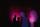 Les silhouettes d’un homme et d’une femme qui se font face et se tiennent devant un mur sombre éclairé de taches de lumière violette.