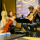 Une violoncelliste et un guitariste discutent et jouent de la musique ensemble dans un café.