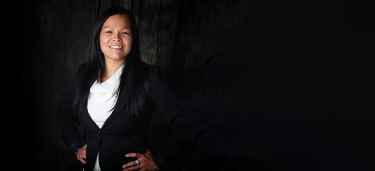 Une femme souriante, les mains sur ses hanches, regarde vers l’objectif. Visibilité masquée.