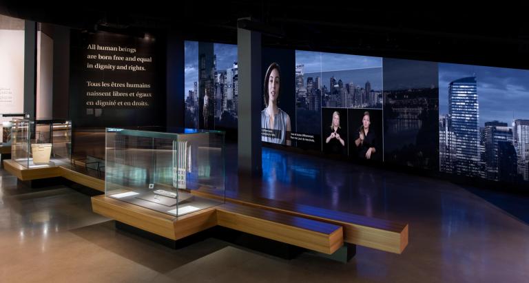 Une galerie avec des vitrines d’exposition et des bancs. Visibilité masquée.