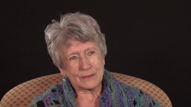 Photo en buste d’Huberte Gautreau. Elle est assise dans un fauteuil, porte un châle et regarde quelqu’un hors champ. Visibilité masquée.