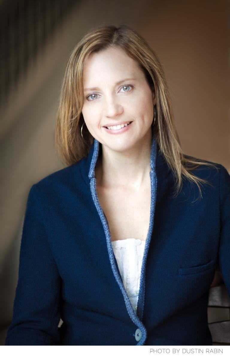 Portrait d’une femme qui sourit et regarde directement vers l’objectif. Visibilité masquée.