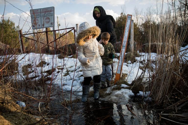 Une mère et deux enfants qui traversent la frontière canado-américaine. Visibilité masquée.