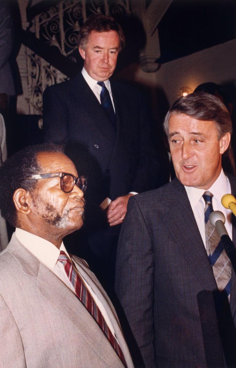 Deux hommes en conversation. Les deux portent des complets.