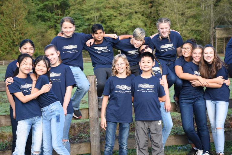 Un groupe de jeunes dehors sur une clôture en bois et posant pour la photo; ils s’embrassent les uns les autres. Visibilité masquée.