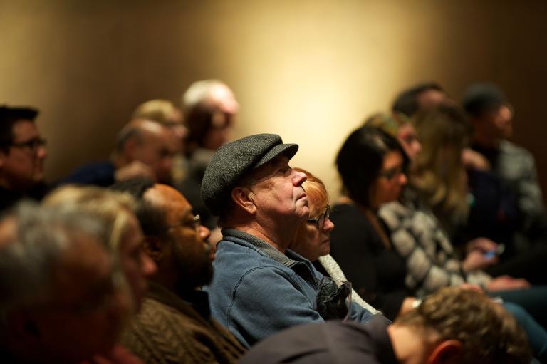 Des gens assis dans un auditoire. Visibilité masquée.