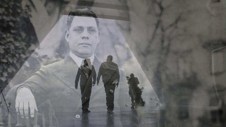 Une image historique translucide d’un homme en complet superposé à une photo contemporaine de deux hommes en silhouette marchant dans un corridor triangulaire. Visibilité masquée.