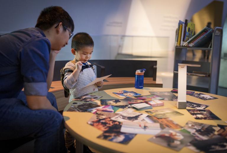 Un enfant et un adulte qui regardent une photographie. Visibilité masquée.