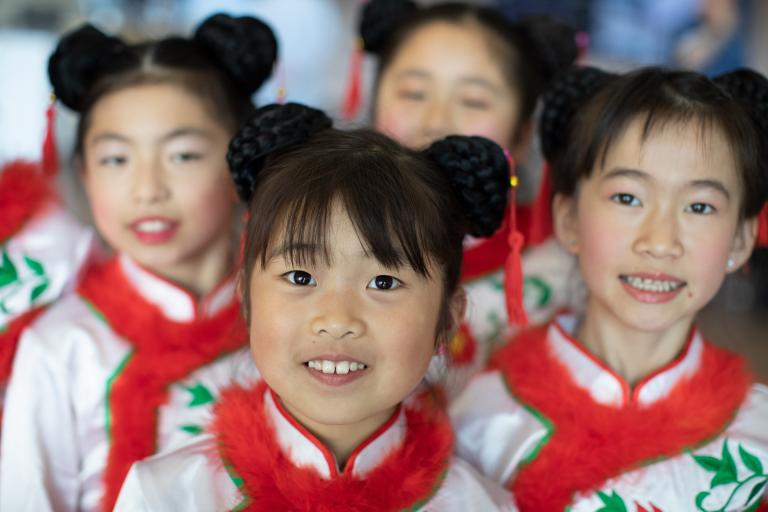 Quatre filles souriantes portant des vêtements assortis en blanc, rouge et vert. Visibilité masquée.