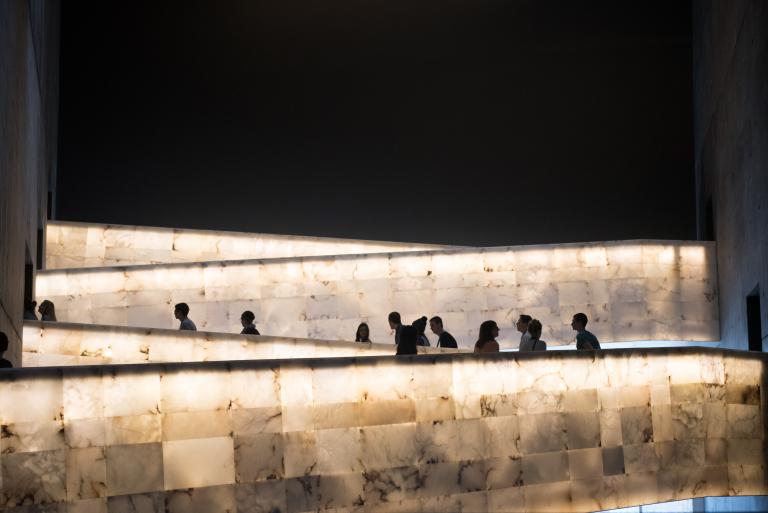 A group of people traveling up the Museum’s lighted alabaster ramps. Visibilité masquée.
