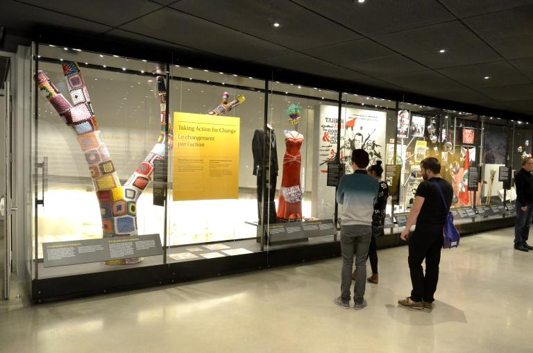 Des membres du public observent une vitrine contenant des images et des objets.
