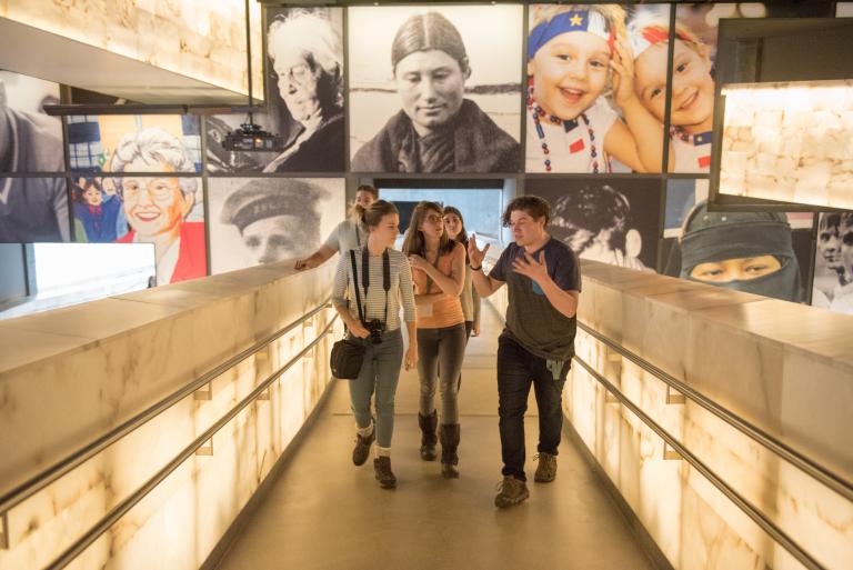 Un groupe de jeunes adultes parlent avec enthousiasme en montant une série de rampes lumineuses. Visibilité masquée.