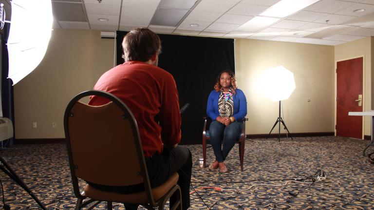 Un homme est assis sur une chaise, le dos tourné vers l’objectif. Une jeune femme est assise en face de lui sur une chaise.