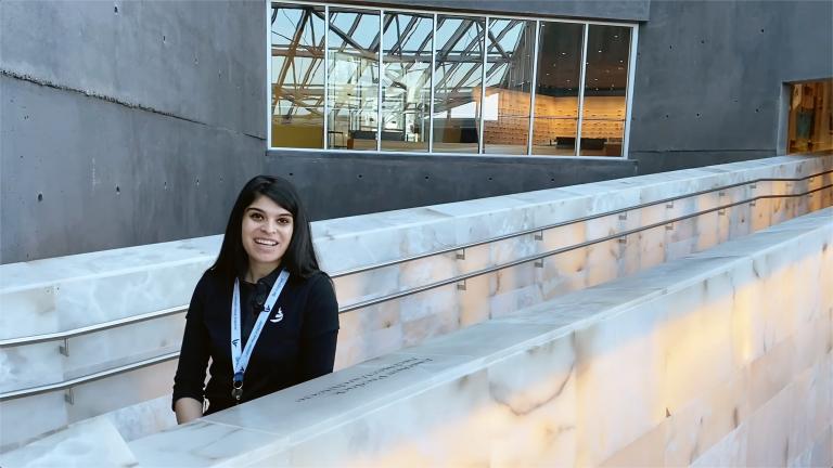 Une femme souriante sur les rampes d'albâtre du Musée. Visibilité masquée.