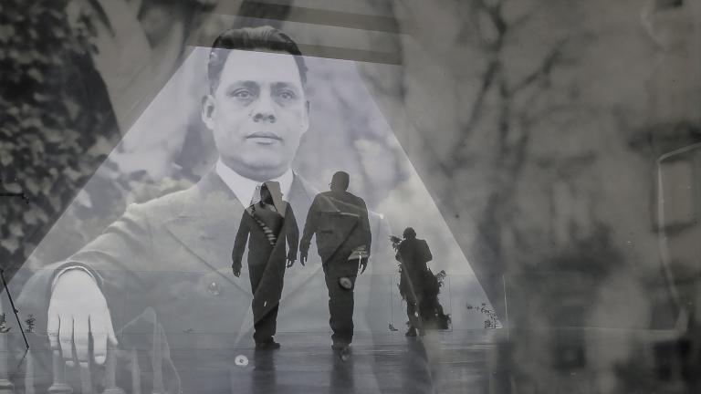 Une image historique translucide d’un homme en complet superposé à une photo contemporaine de deux hommes en silhouette marchant dans un corridor. Visibilité masquée.