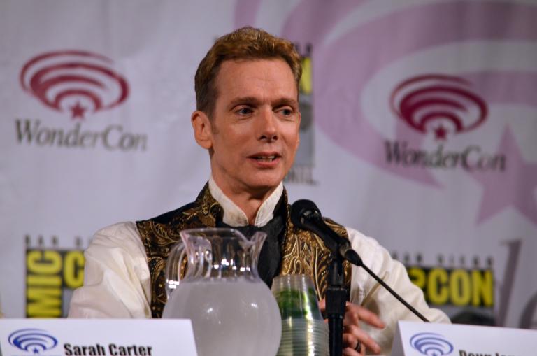 Un homme assis devant un microphone.