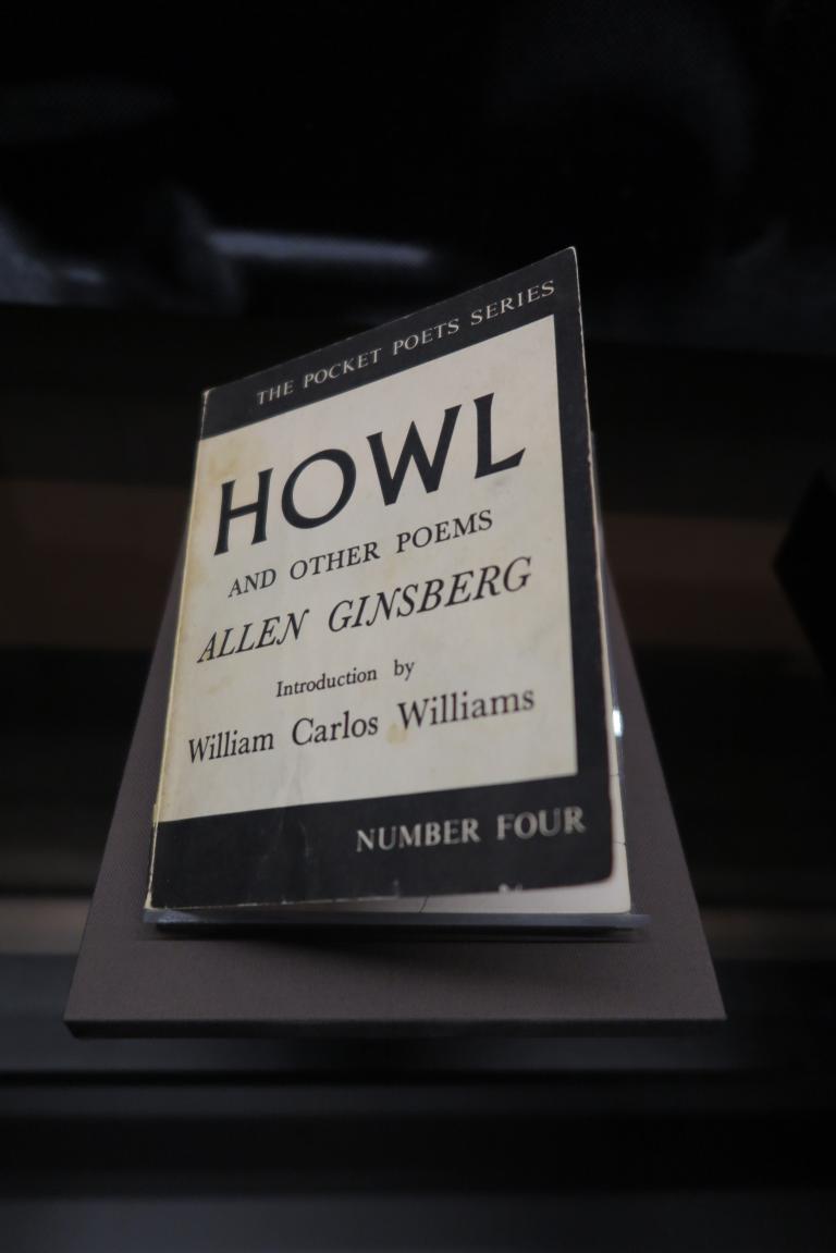 Un livre dans une exposition. Sur la couverture, on peut lire : The Pocket Poets Series. Howl and Other Poems. Allen Ginsberg. Introduction by William Carlos Williams. Number Four. Visibilité masquée.