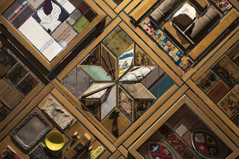 Portion d'une grande oeuvre d'art composée d'objets placés dans des cadres en cèdre. Visibilité masquée.