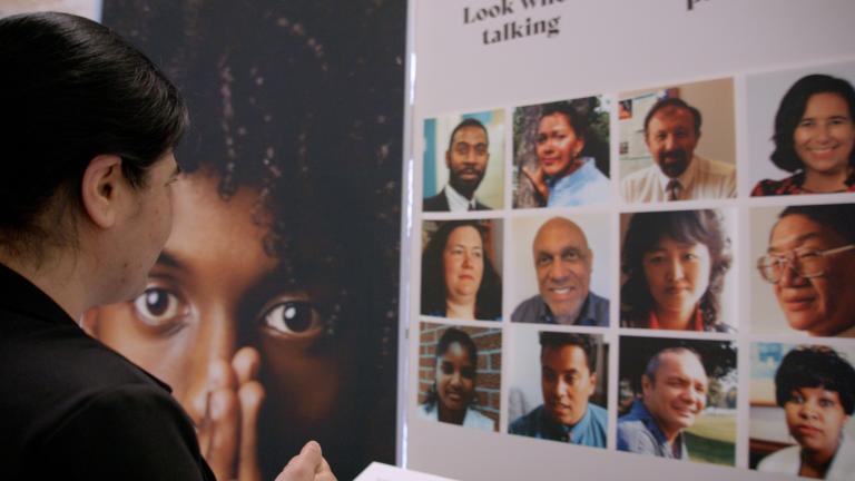 A woman gazes at a display showing faces of a diverse group of people. Visibilité masquée.