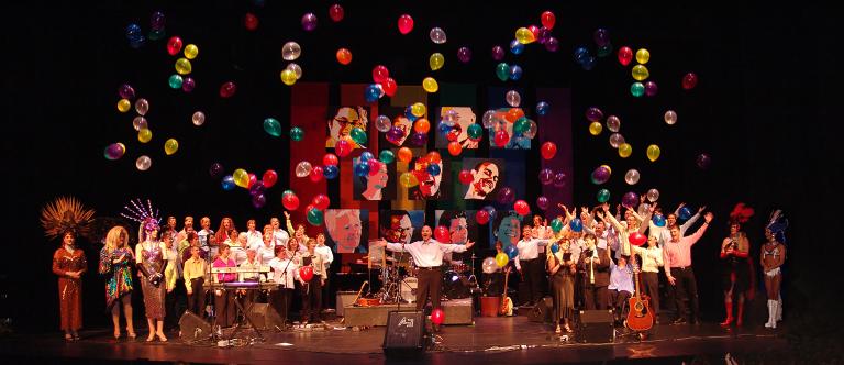 La chorale Rainbow Harmony Projet chantant sur une scène en bois dans une église. Visibilité masquée.