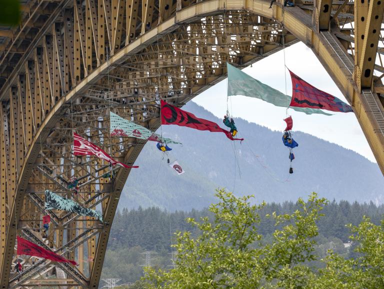 Plusieurs grandes bannières triangulaires sont suspendues au bas d’un grand pont.