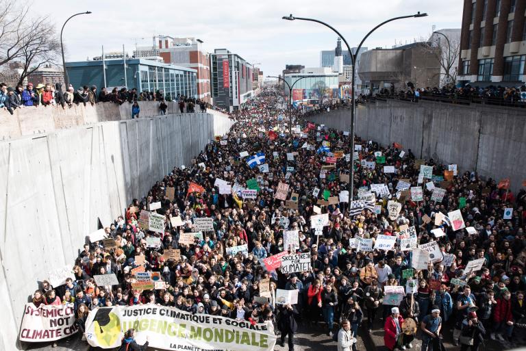 Des milliers de personnes tiennent des pancartes et des bannières de protestation et défilent dans la rue.