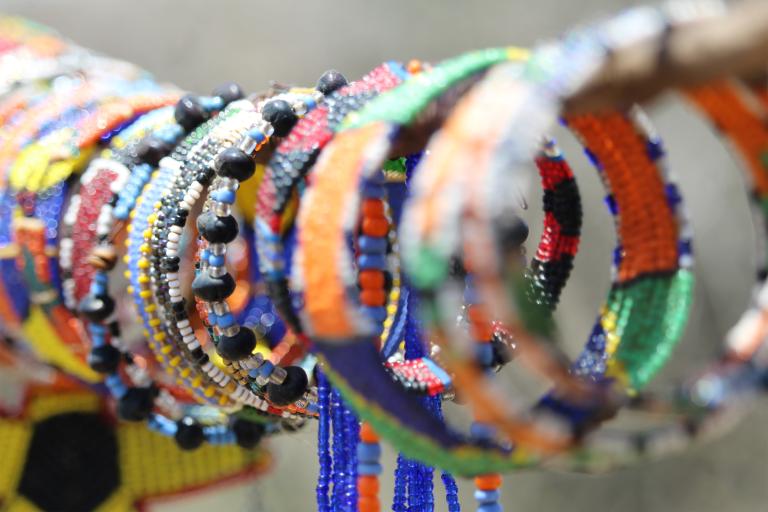 Un étalage de bracelets en perles colorés est présenté à la vente. Visibilité masquée.