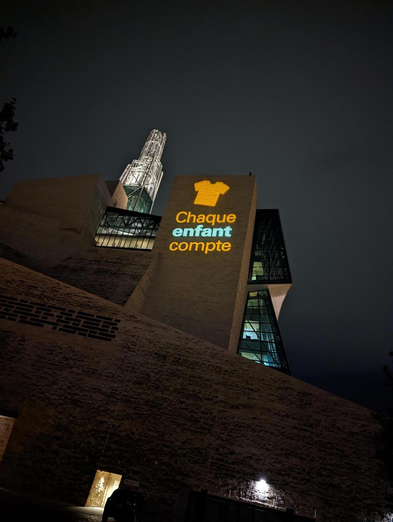 L’image d’une chemise orange avec les mots Chaque enfant compte est projetée sur un mur extérieur du Musée. Visibilité masquée.