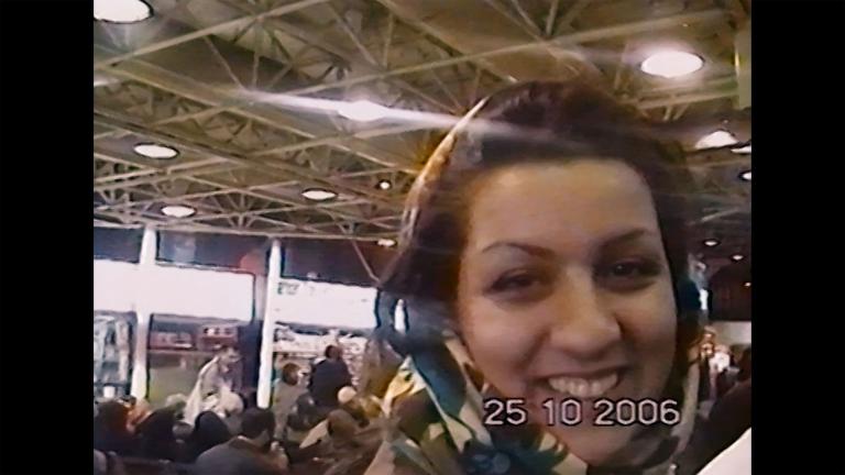 Une jeune femme souriante portant un foulard se tient dans une foule. L’image est datée : 25-10-2006. Visibilité masquée.