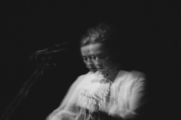 Photo en noir et blanc de Sarah Harmer jouant de la guitare. Deux images floues semblent juxtaposées l’une sur l’autre. Visibilité masquée.