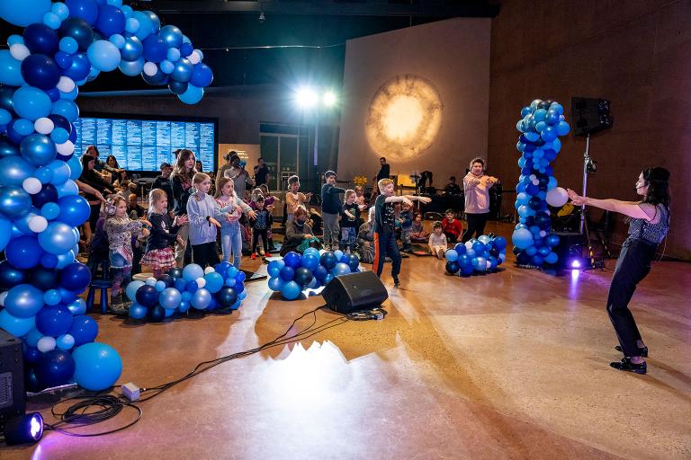 Des jeunes dansent dans une salle remplie de ballons bleus. Visibilité masquée.
