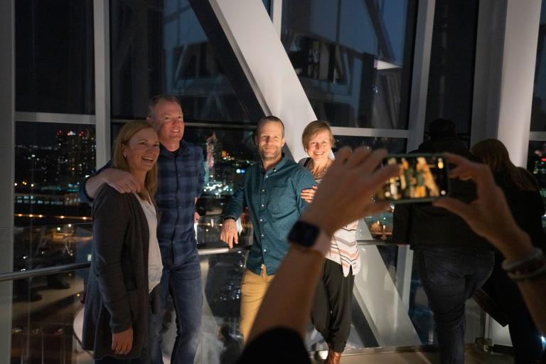 Deux couples souriants posant pour une photo dans la tour du Musée. Visibilité masquée.