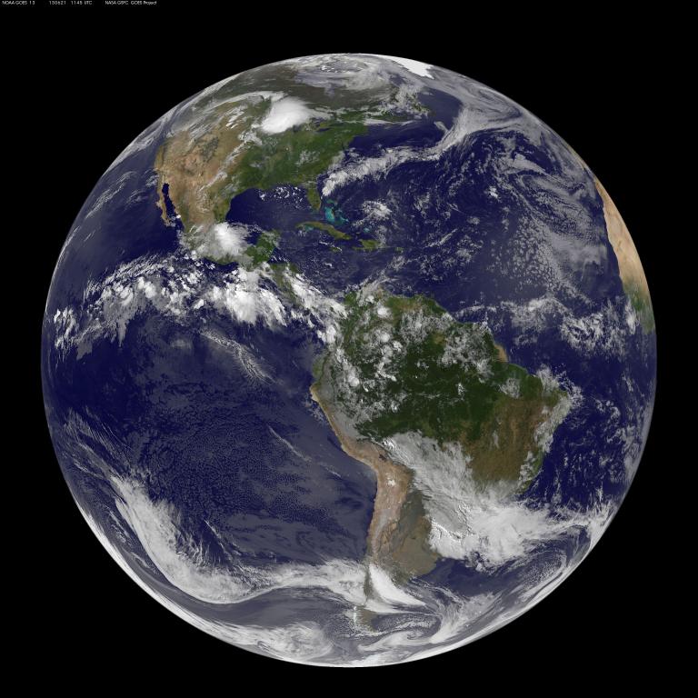 Une vue panoramique de la Terre depuis l’espace, centrée sur l’Amérique du Nord et l’Amérique du Sud, avec des nuages blancs tourbillonnant au-dessus d’océans bleus et de masses continentales vertes et brunes. Visibilité masquée.