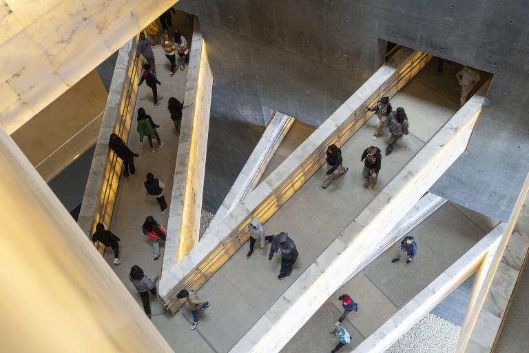 Des élèves marchent sur les passerelles qui relient les différents niveaux des galeries du musée. Visibilité masquée.